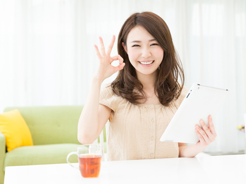 部屋でタブレットを見る女性